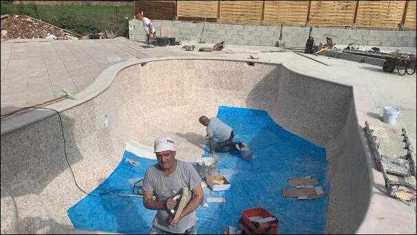 SJM Plastering team applying sand-and-cement external render to a swimming pool basin